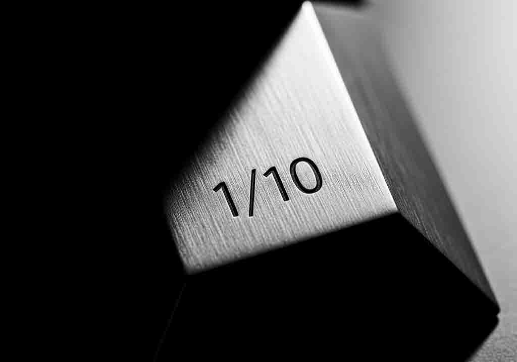 Nahaufnahme eines metallischen, dreieckigen limitierte edition Objekts, auf dem die Zahl '1/10' eingraviert ist.